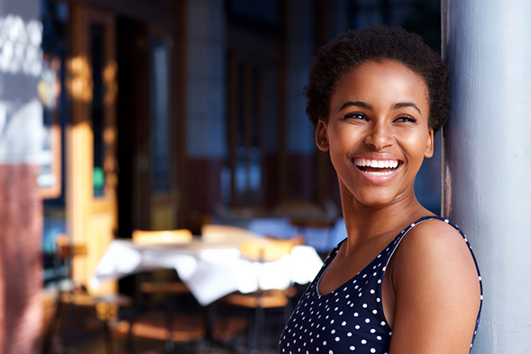 Woman smiling, leaning up against a wall