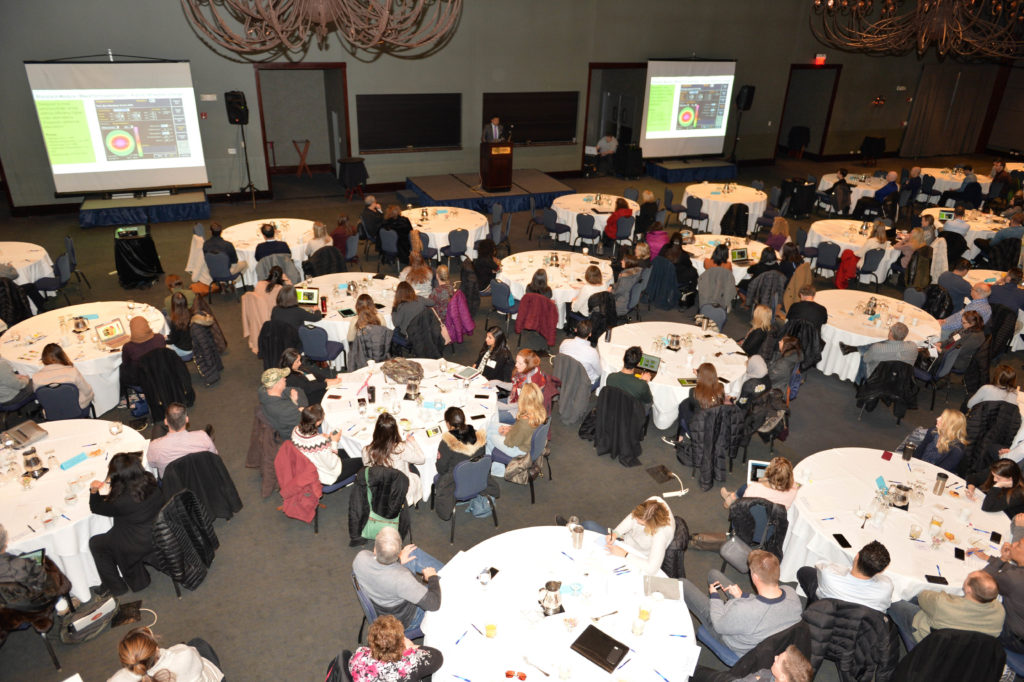 people sitting at tables during a presentation