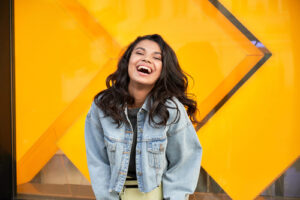 smiling woman standing in front of orange background 