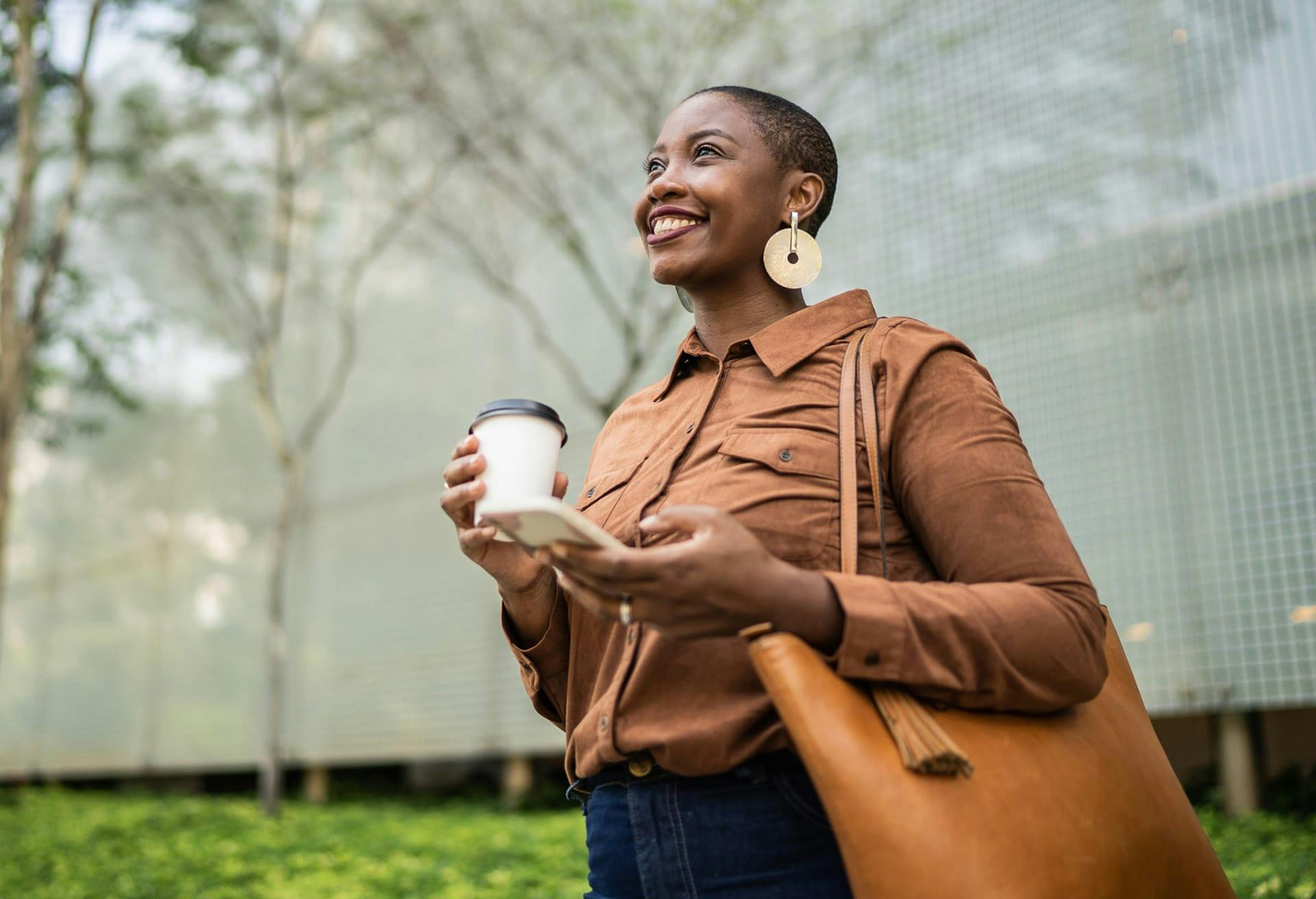 woman walking outside holding a coffee cup