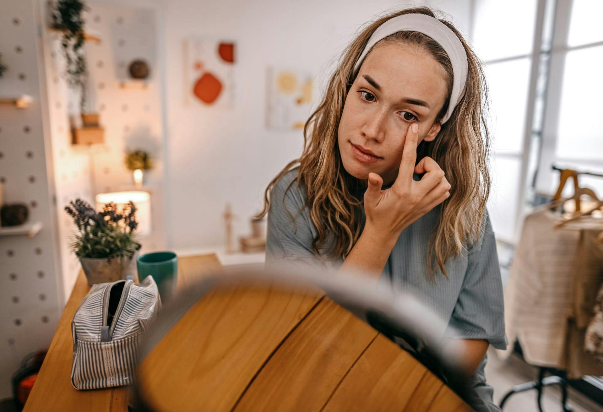 woman looking in a mirror touching near her eye