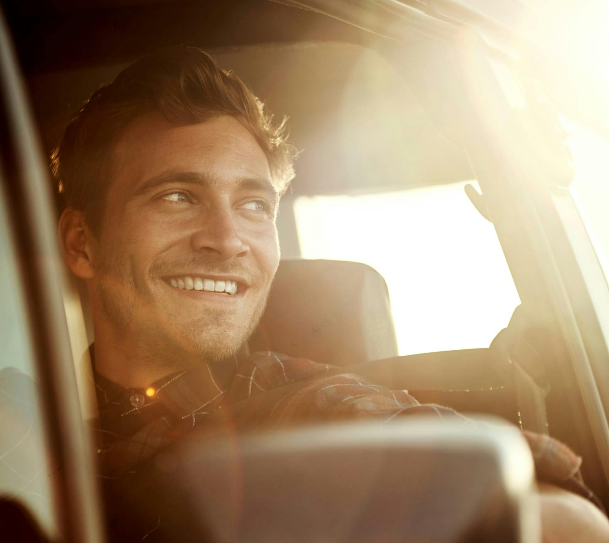 Man looking out the window of his car during the sunset