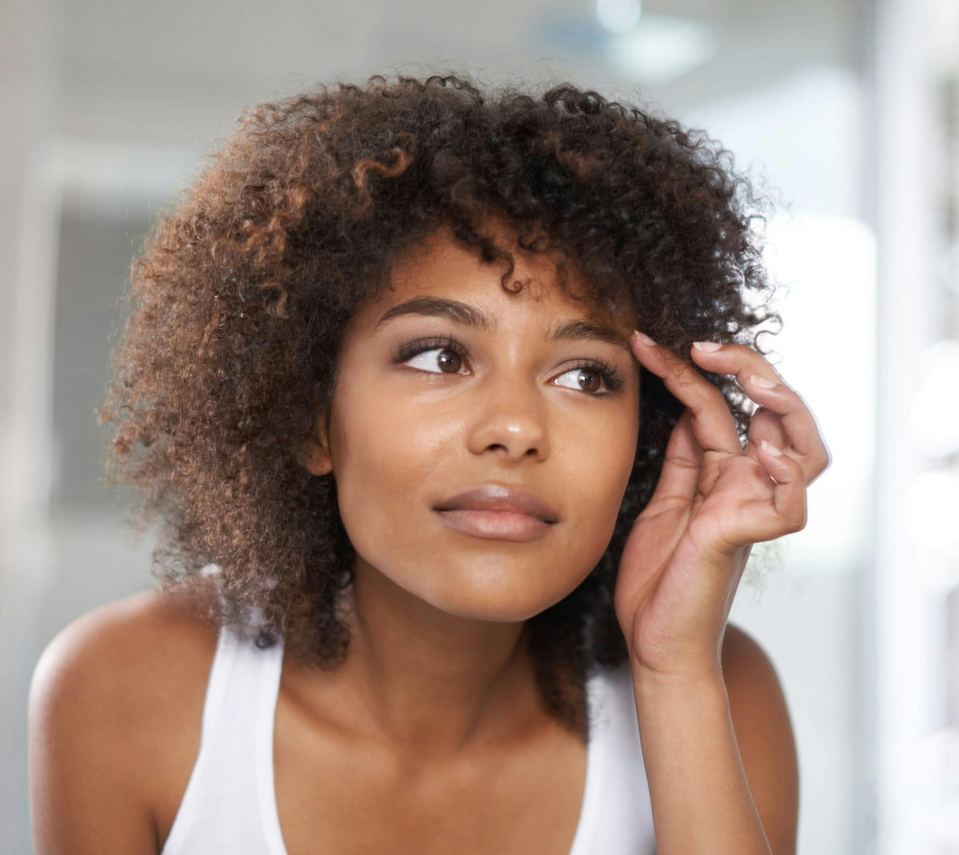 woman with curly hair looking in the mirror