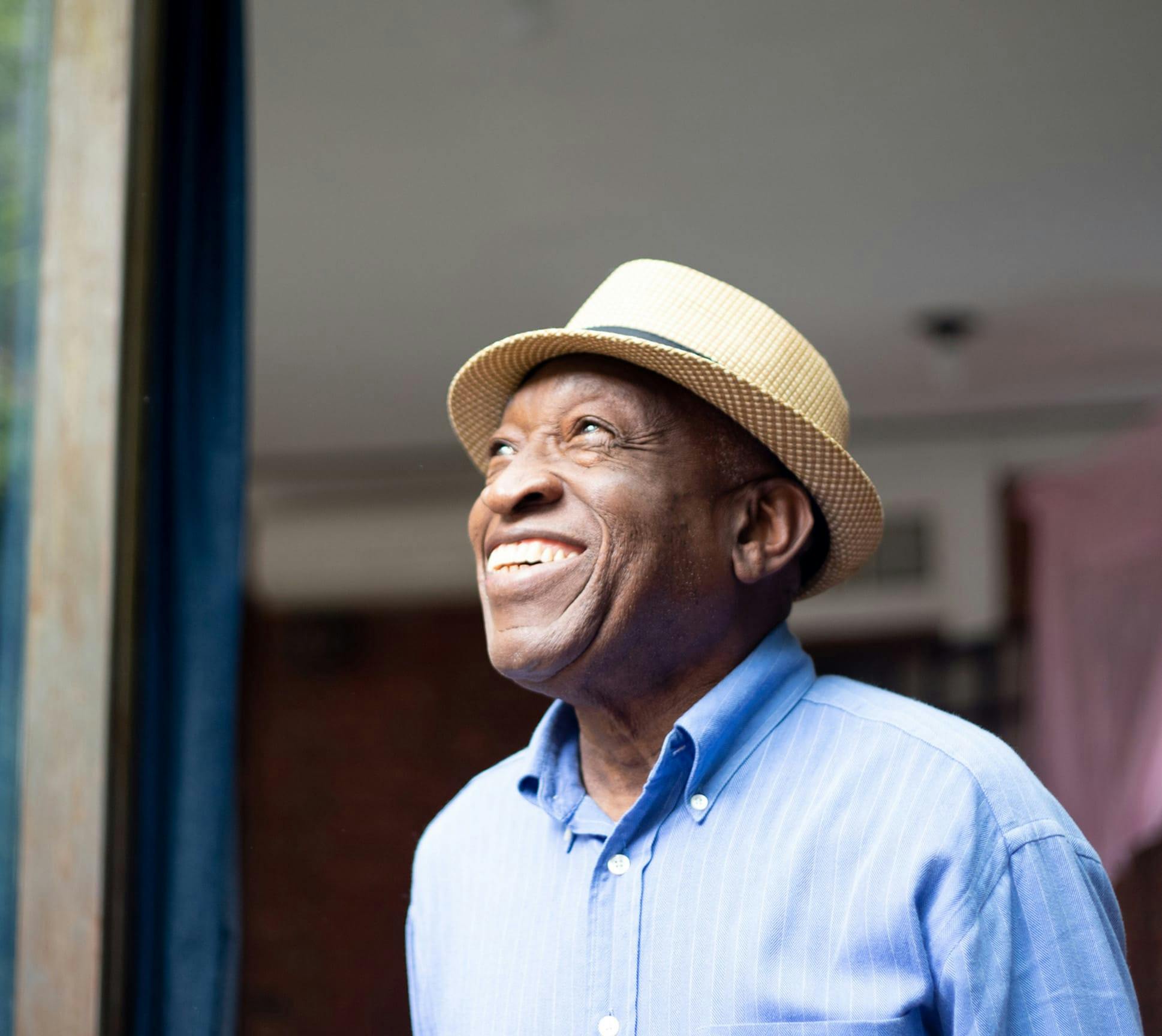 Older man outside wearing a top hat and long sleeve blue shirt
