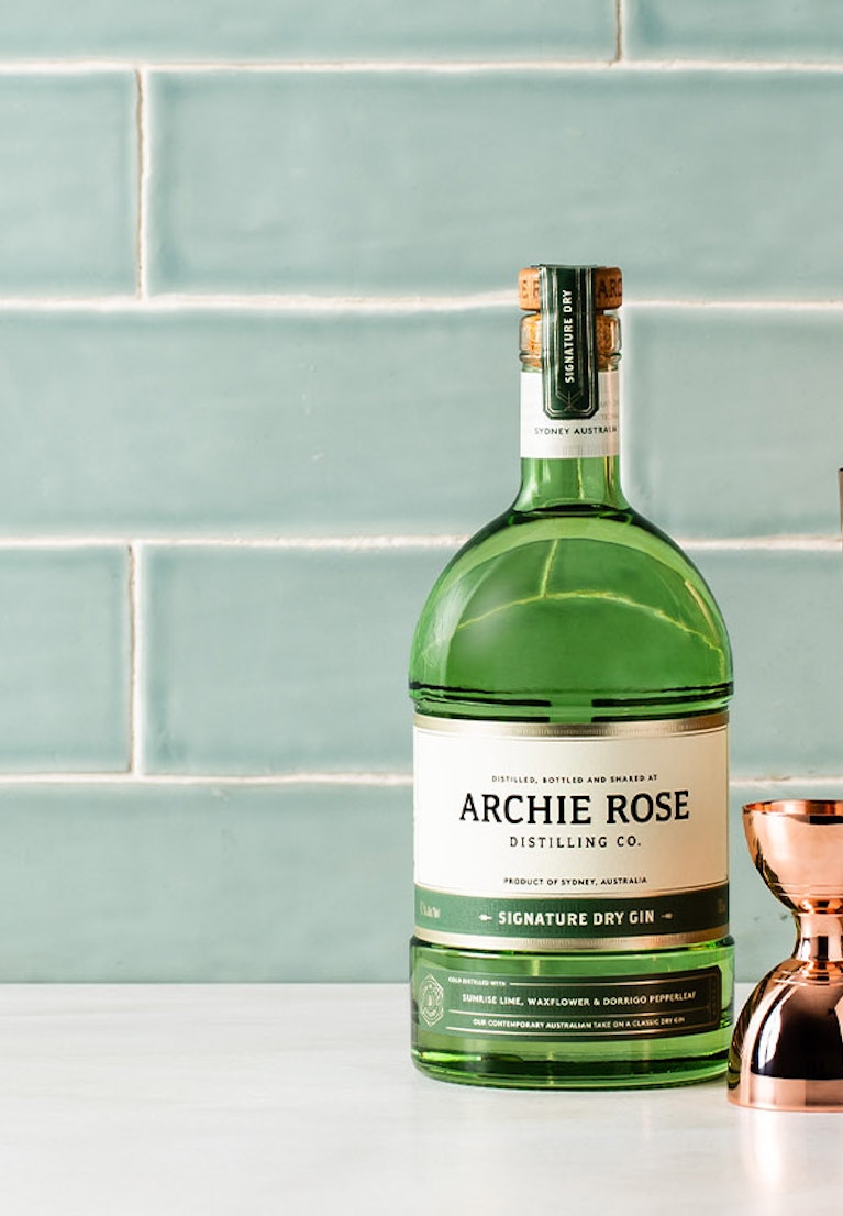 Archie-Rose-Signature-Dry-Gin-with-copper-Toby-Shaker-copper-Hawthorn-strainer-and-graduated-copper-bell-jigger-sitting-on-a-bench