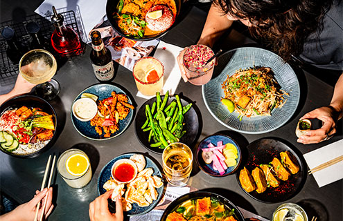 a table full of delicious wagamama food and drink being enjoyed by a group of friends