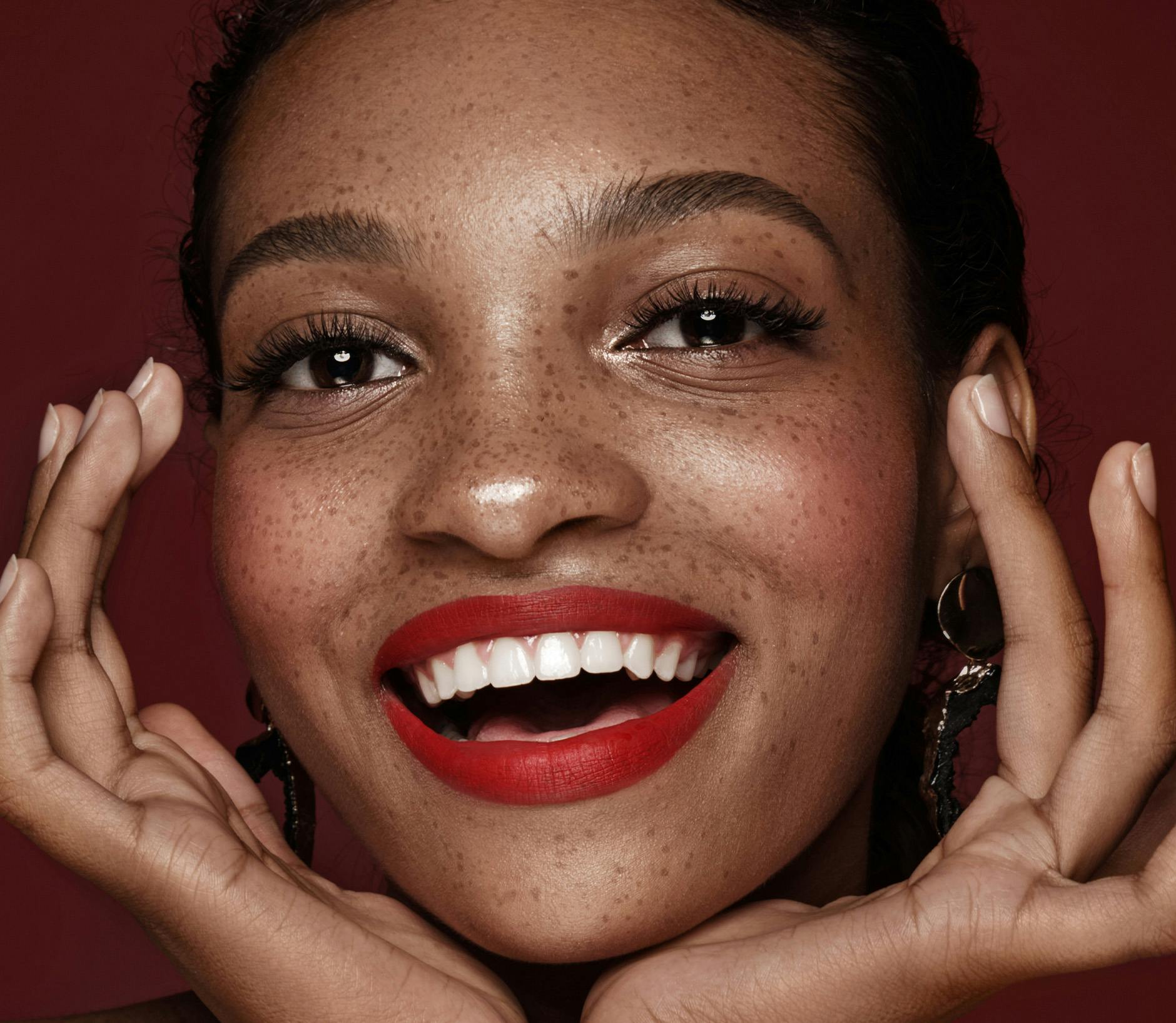 Woman with red lipstick and freckles smiling