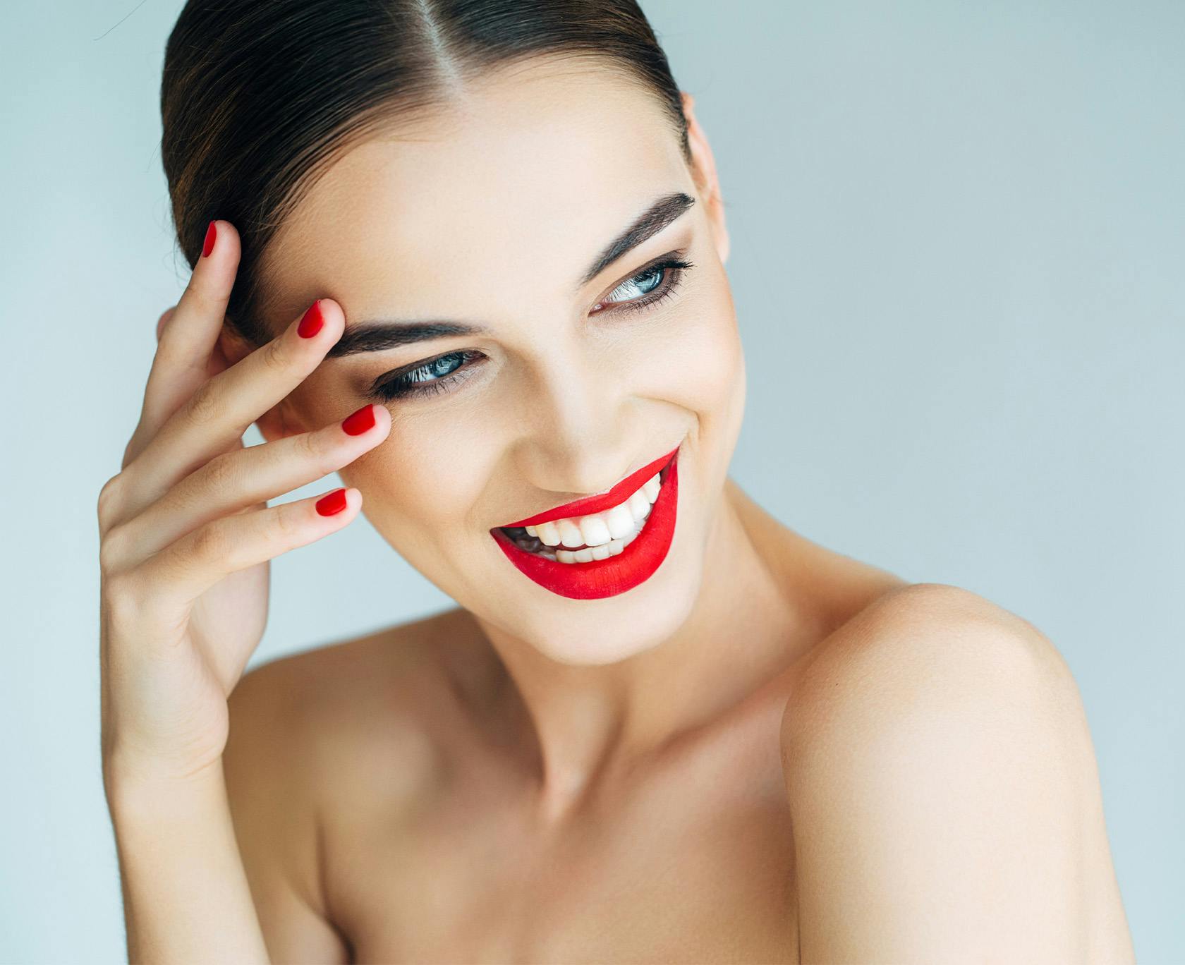 Woman with red lipstick and nail polish smiling