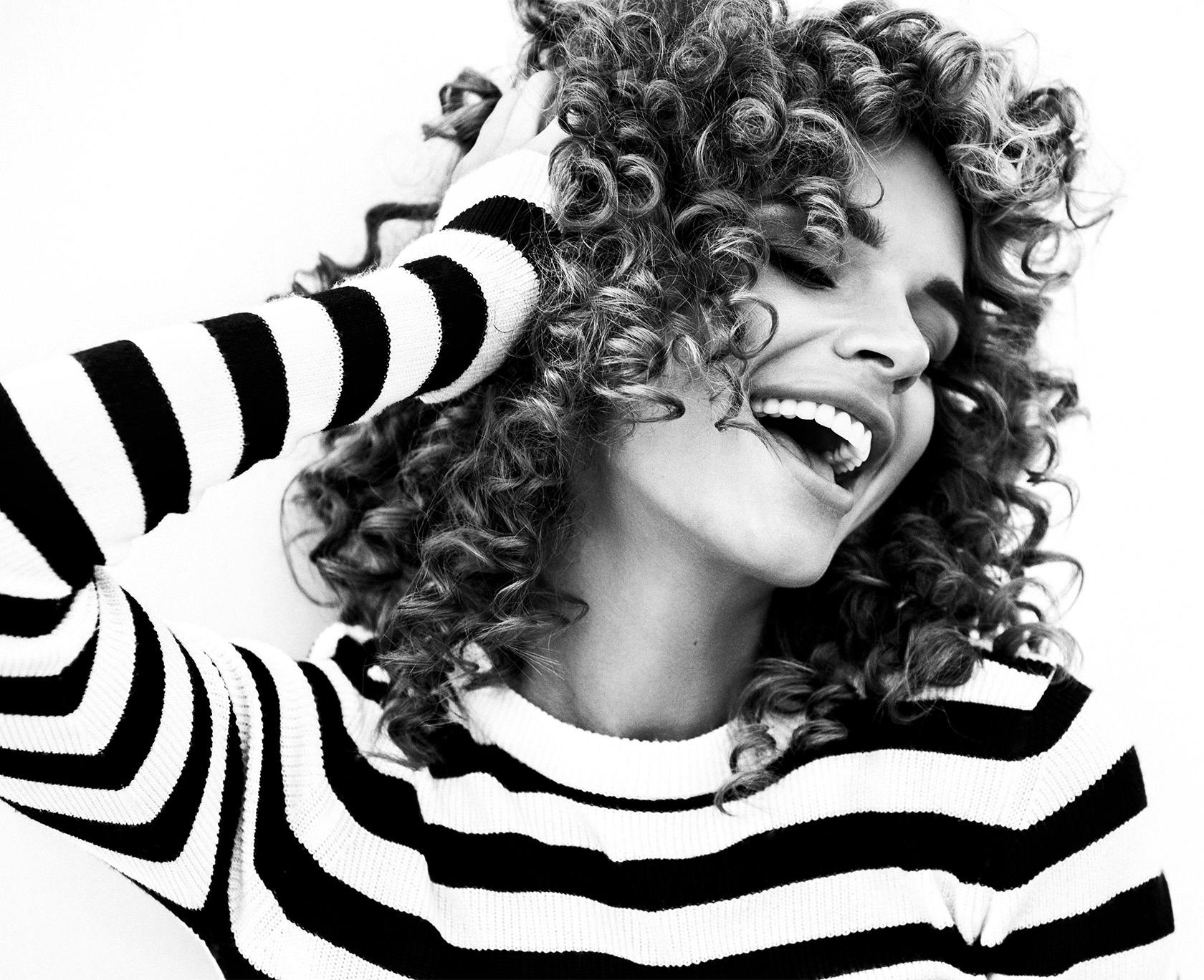 Black and white photo of woman with curly hair smiling