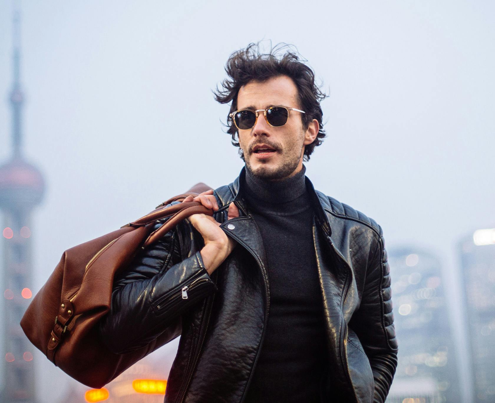 Man in black turtleneck holding a bag