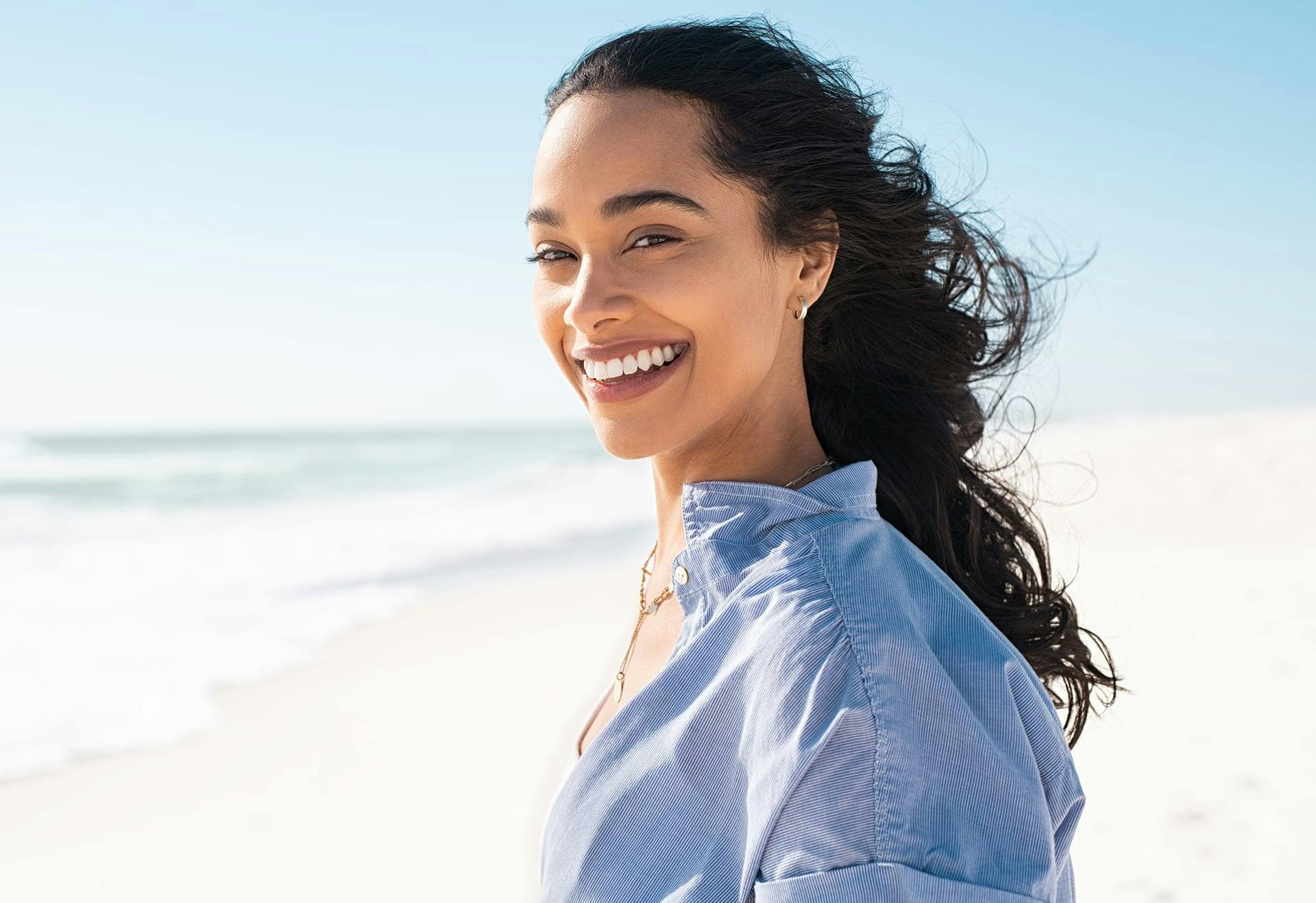 Woman with dark hair smiling on the beach
