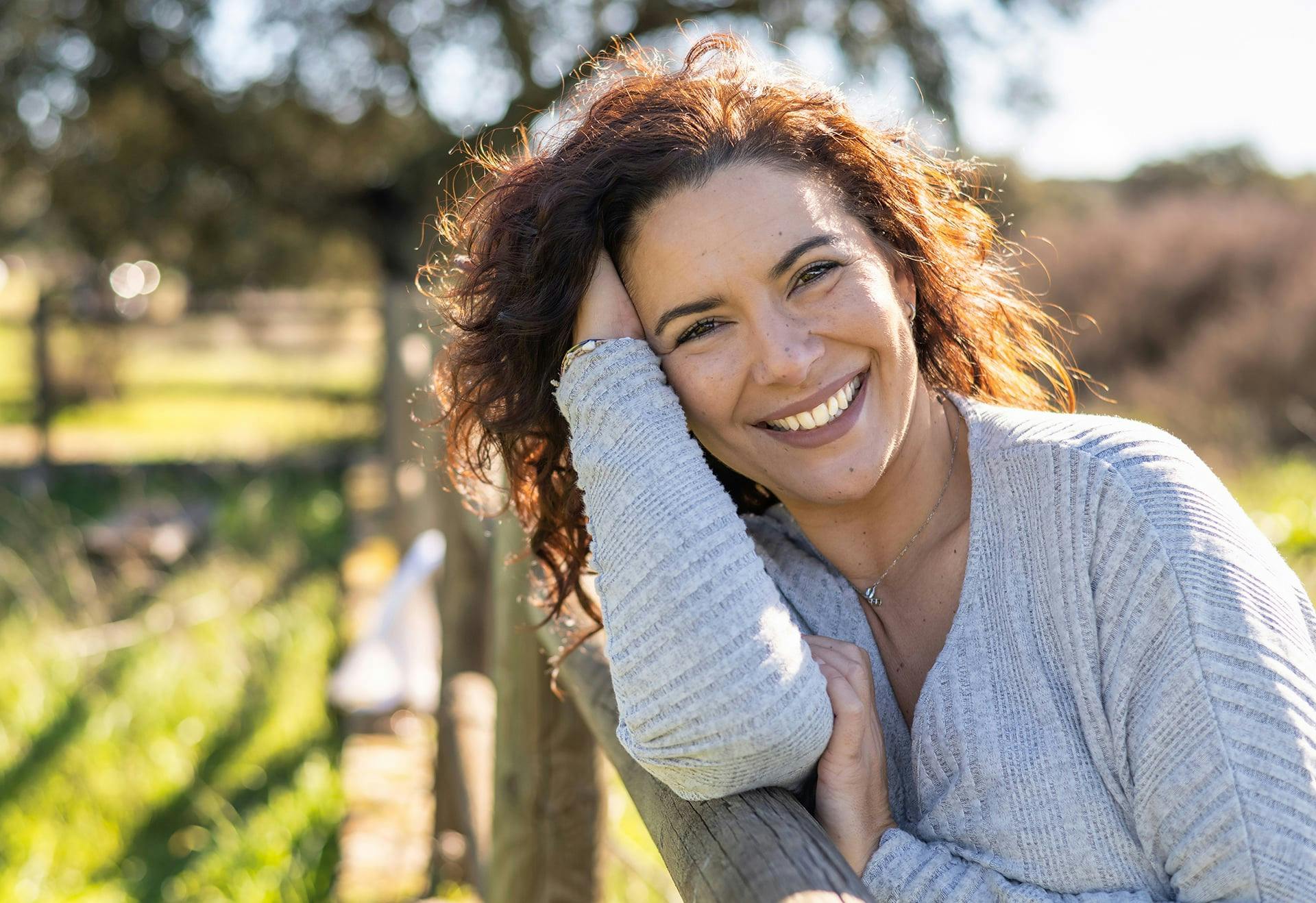 Woman leaning against a fence with her arm on top of it