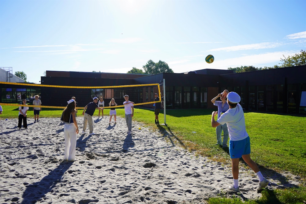 udklædte elever spiller beach volley