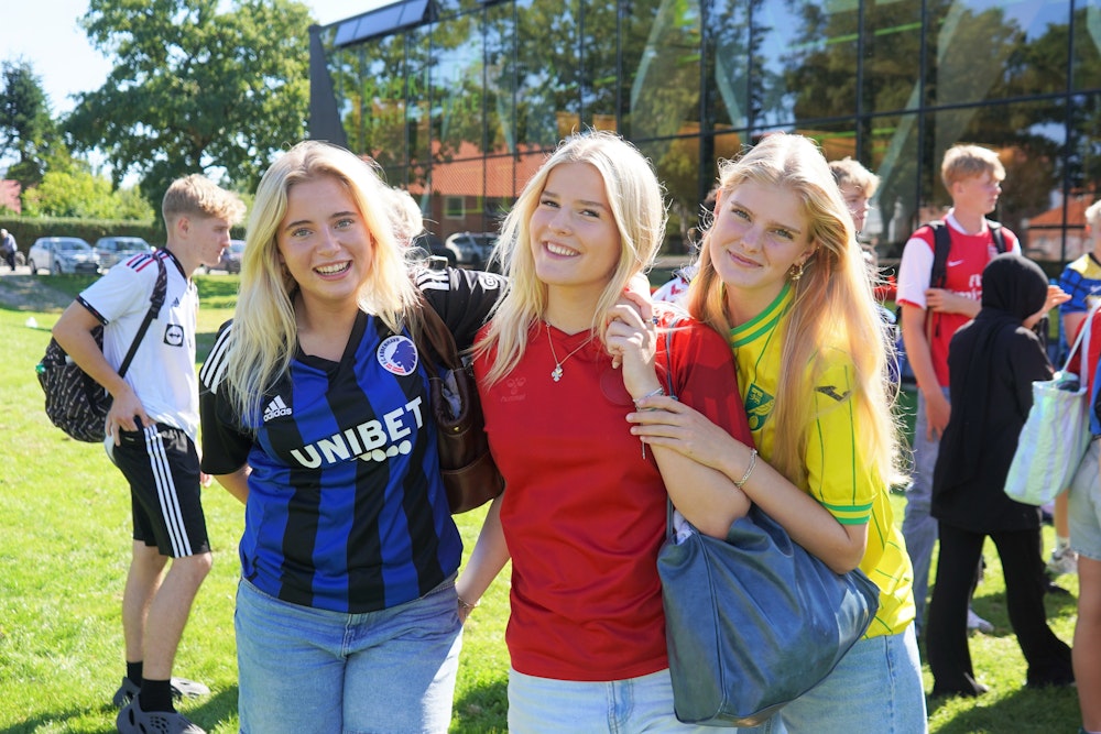 Tre smilende piger i fodboldtrøjer til aktivitetsdag