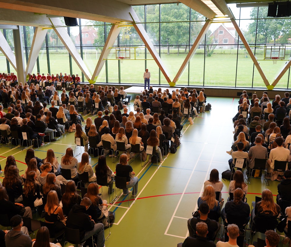 Klasser samlet i gymnasiets hal, mens rektor byder velkommen til første skoledag