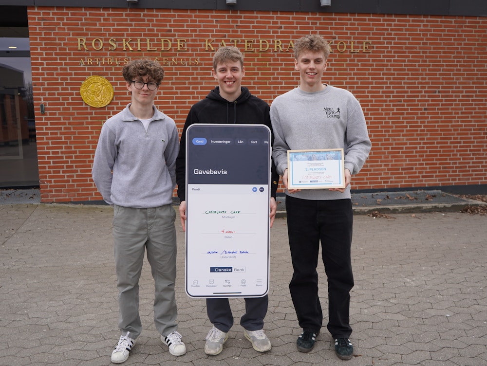 Tre elever står foran RKS med kæmpe gavekort og diplom efter priser til Company Programme Entreprenørskab