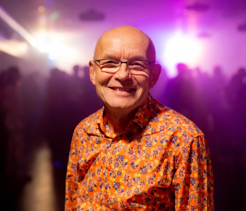 Nærbillede af rektor Claus Niller foran en sløret flok elever til fest på gymnasiet