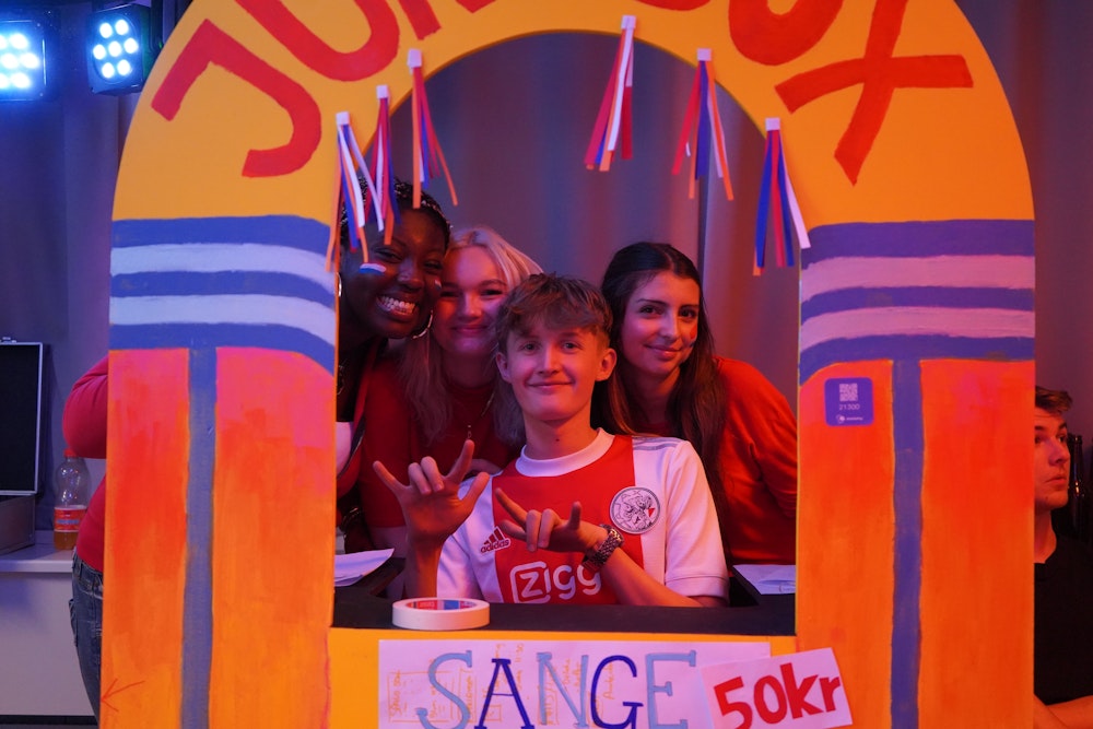 Billede af fire smilende elever til studietursfesival, som står bag deres bod hvor de sælger sange