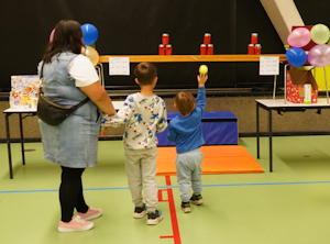 Billede fra studietursfestivalen hvor to drenge står med deres mor og kaster efter dåser