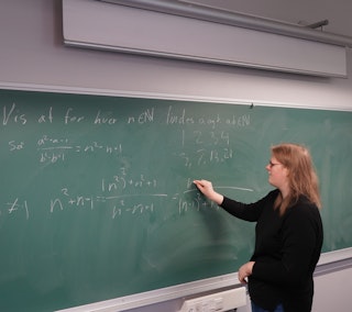 En elev står ved tavlen og løser en matematikopgave