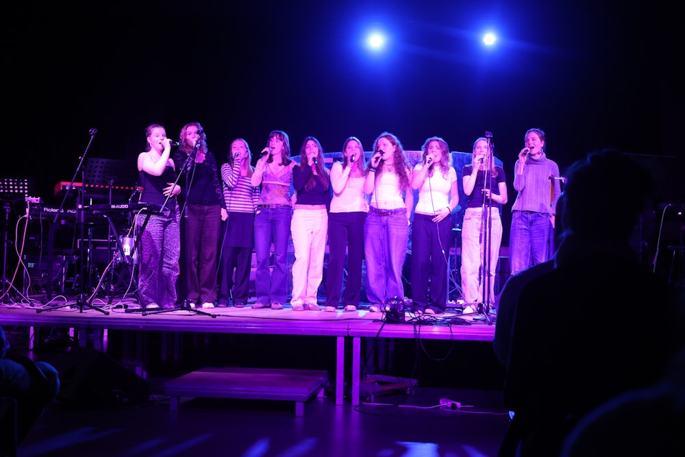 En gruppe piger der står på scenen og synger til forårskoncert 2025