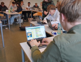 En elev sidder og programmerer i et klasseværelse