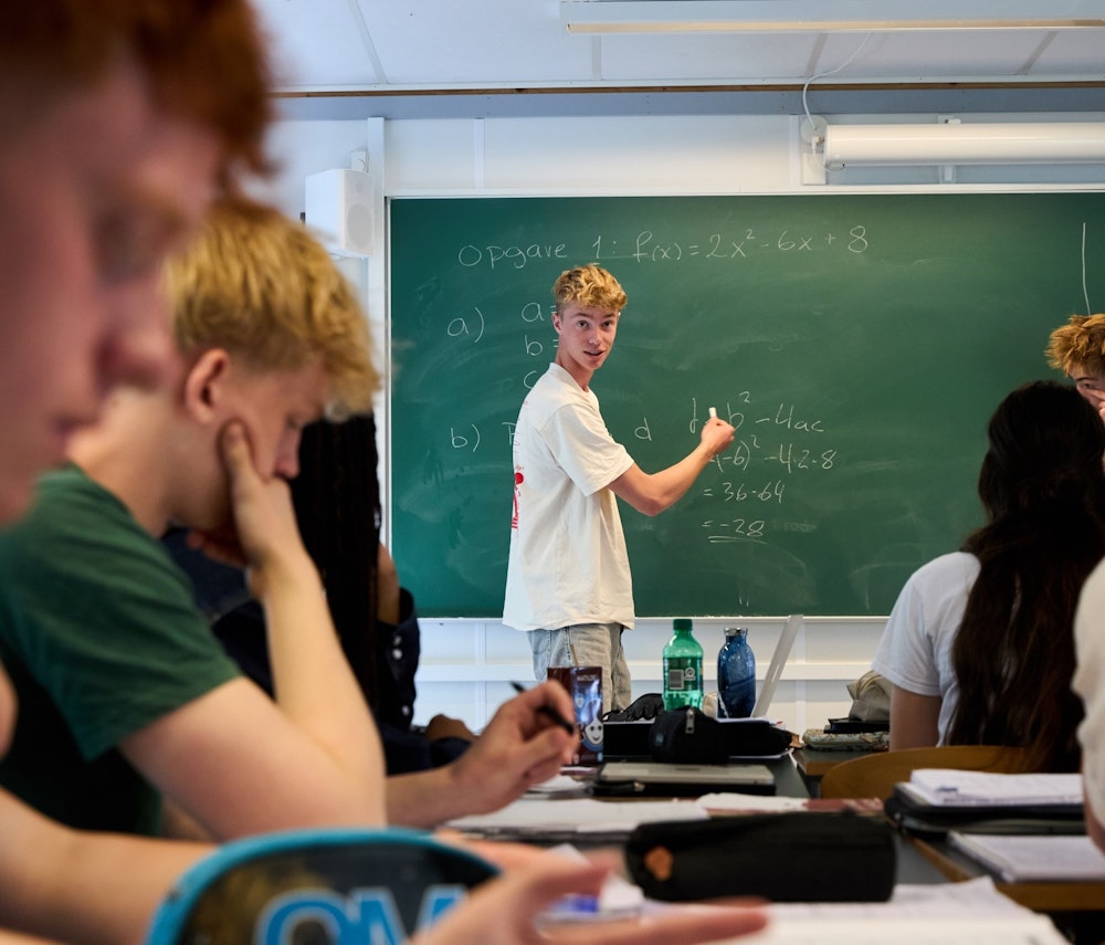 En elev står ved tavlen og forklarer matematik