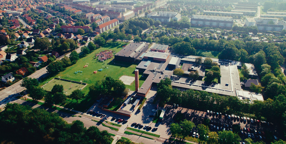 et luftfoto af hele skolen og de grønne arealer med elever samlet på boldbanerne