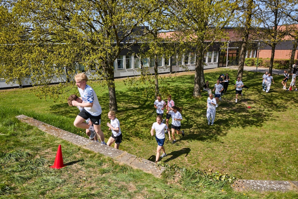 Idrætselever i fuld fart op ad en trappe foran skolen