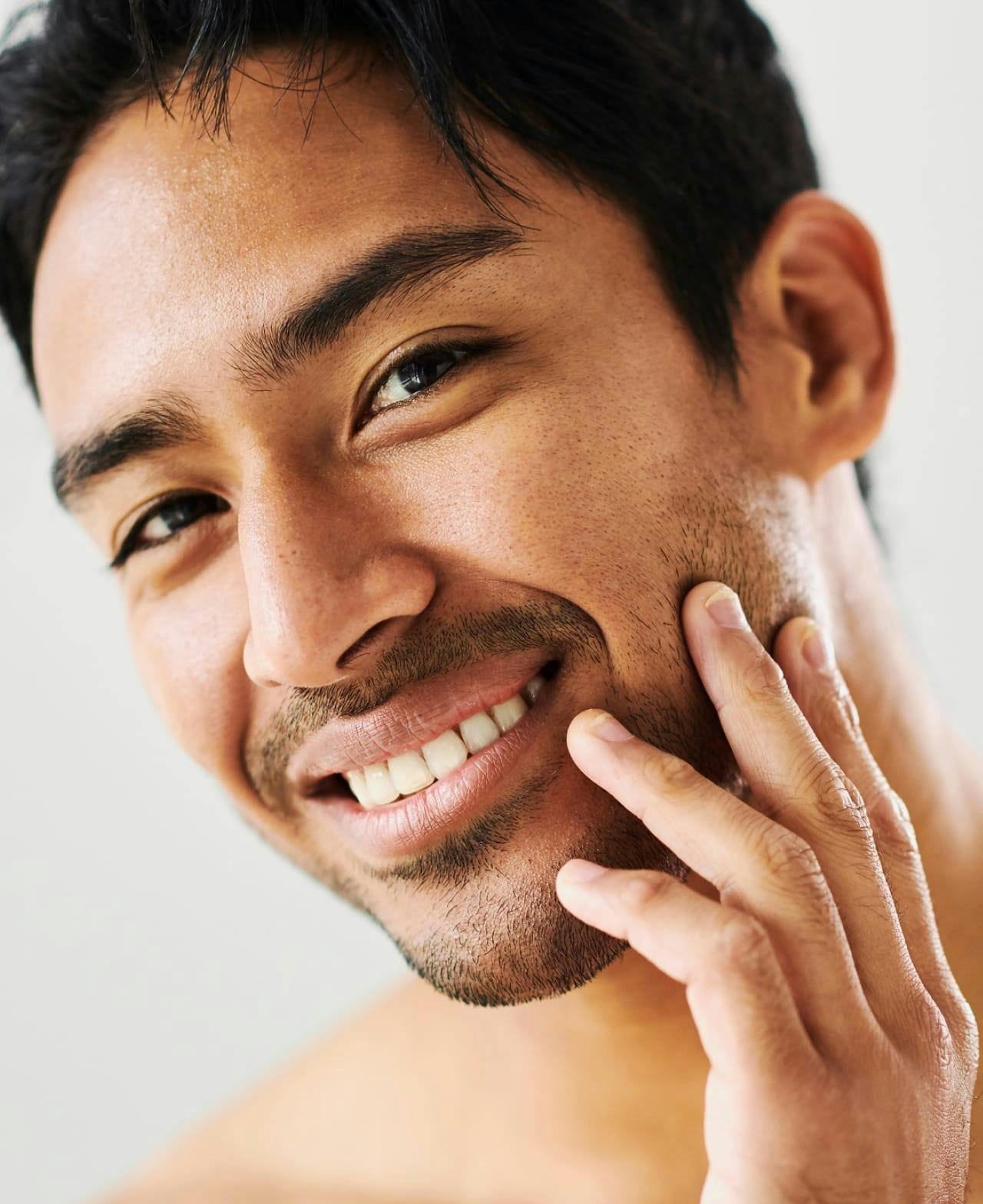 Man smiling and touching his cheek