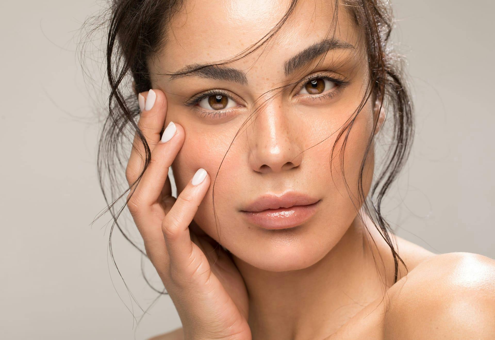 Woman with hair in her face and her hand on her cheek