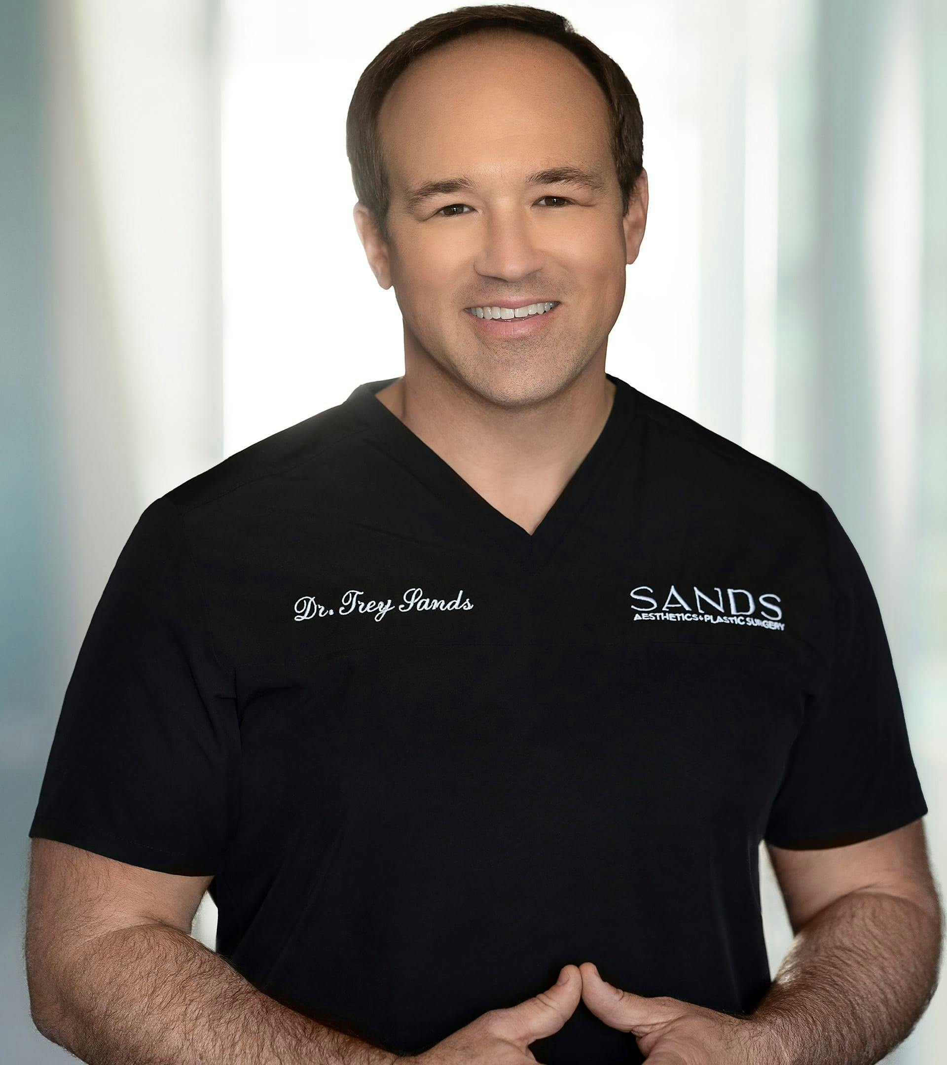 Dr. Trey Sands in black scrubs posing for camera