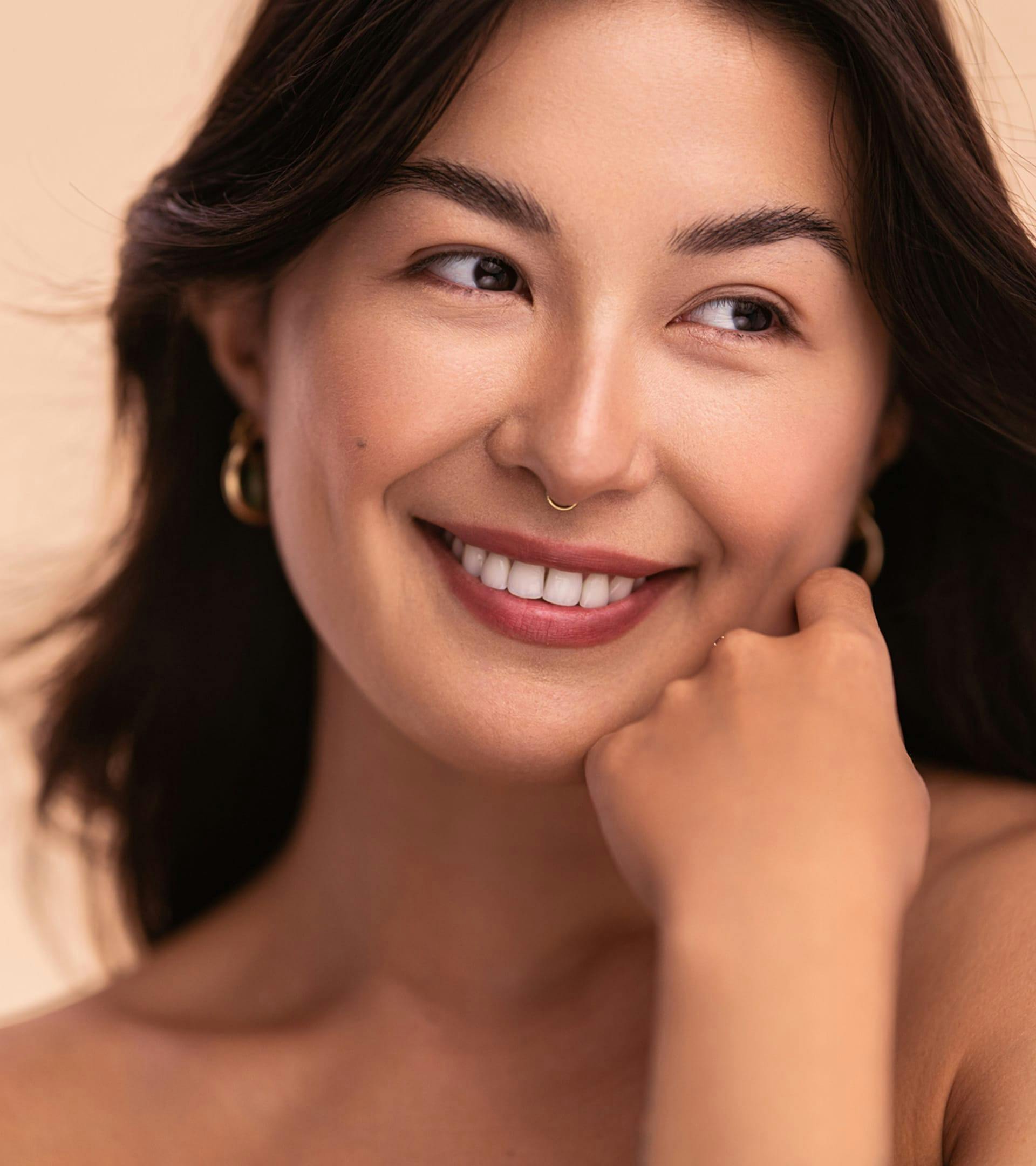 close up of a woman with long dark hair smiling and posing for the camera