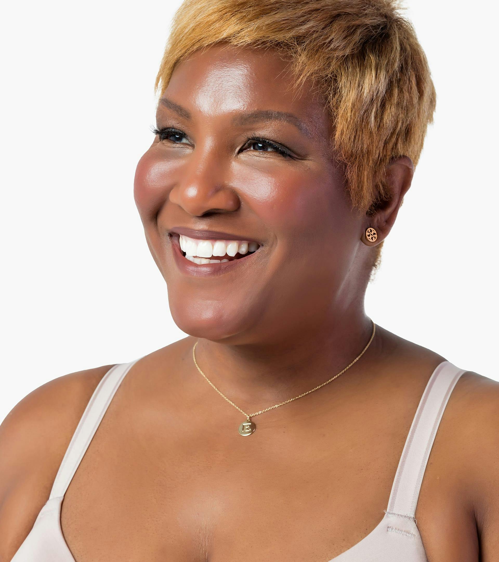 close up of a woman with short blonde hair wearing a white bra top smiling at camera
