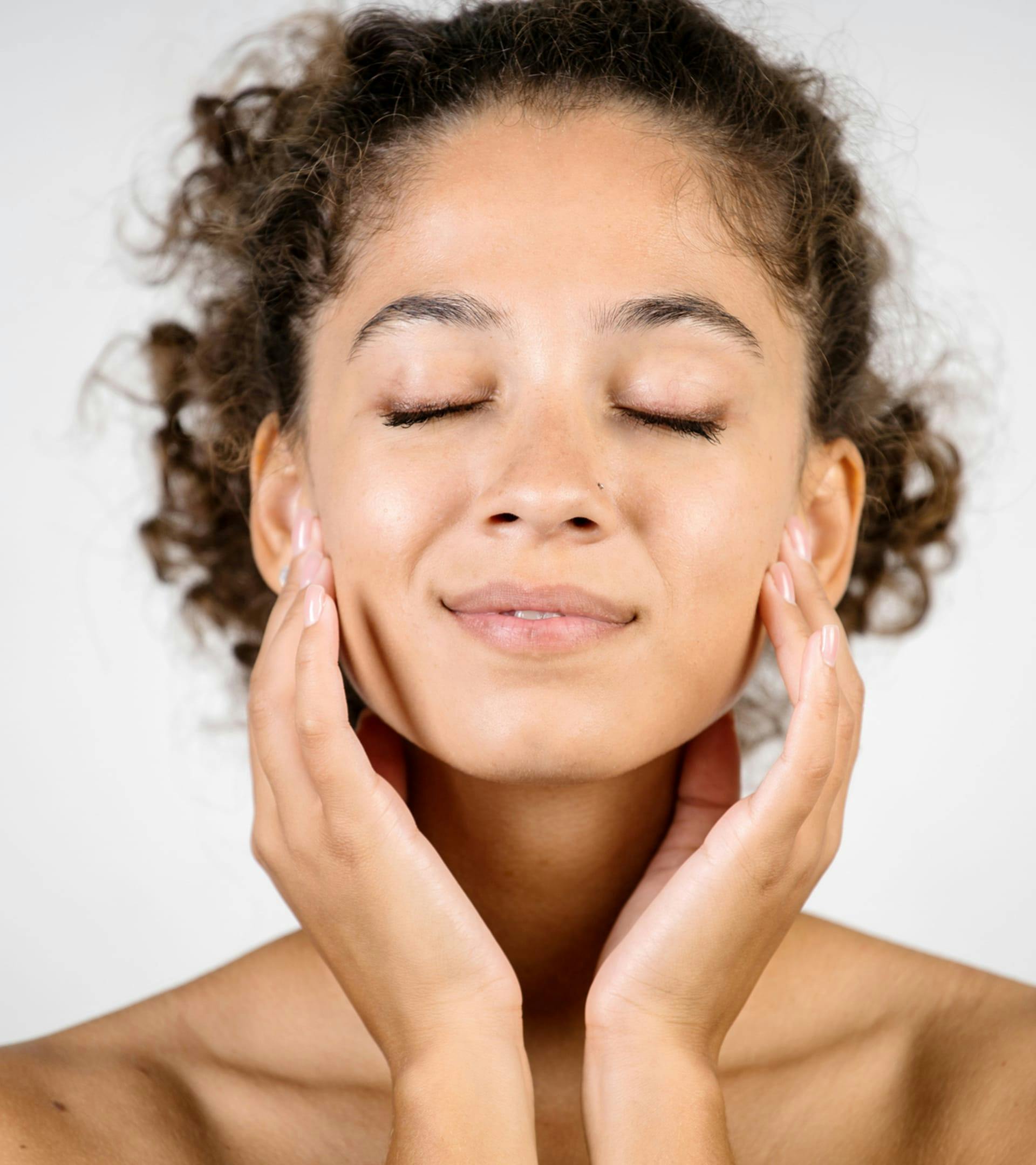 close up of woman with her eyes closed and her hands on her face