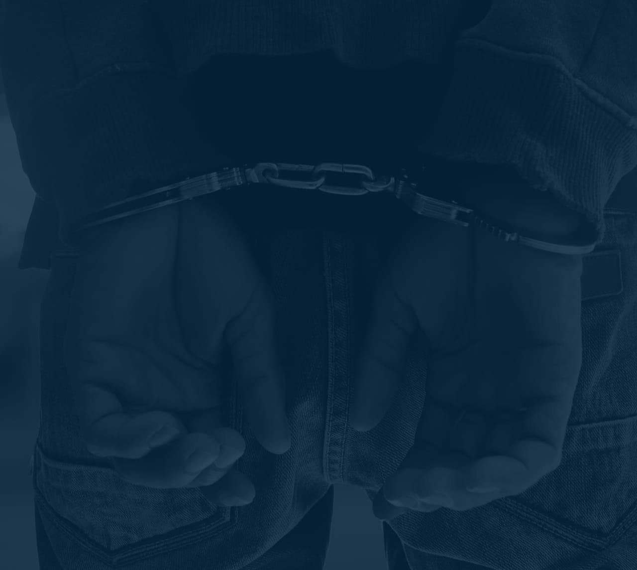 Person in handcuffs, image has a blue filter over it