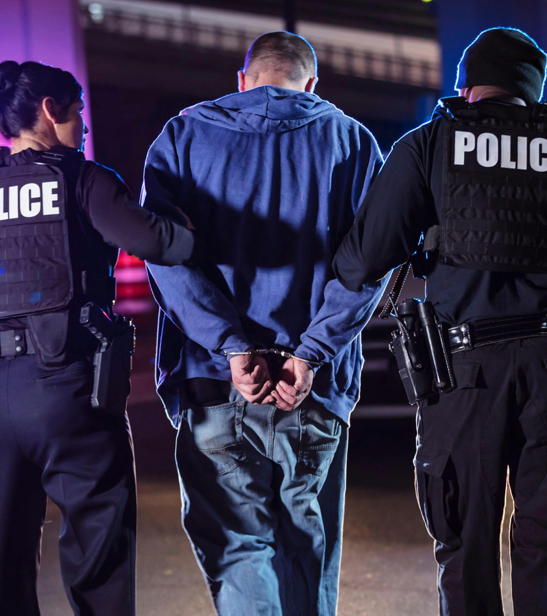 Handcuffed man walking with police.