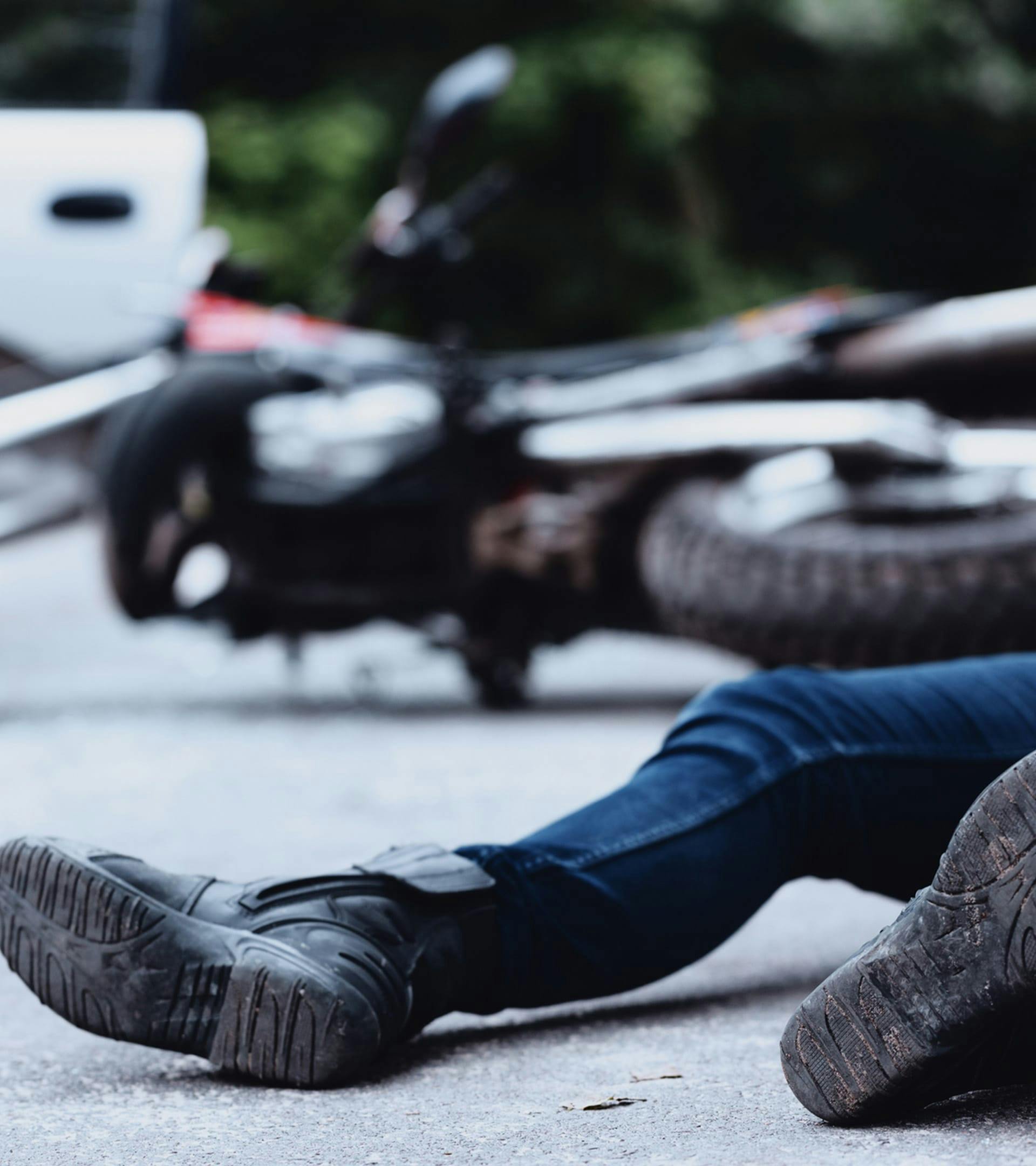 Man on the ground next to an overturned motorcycle.