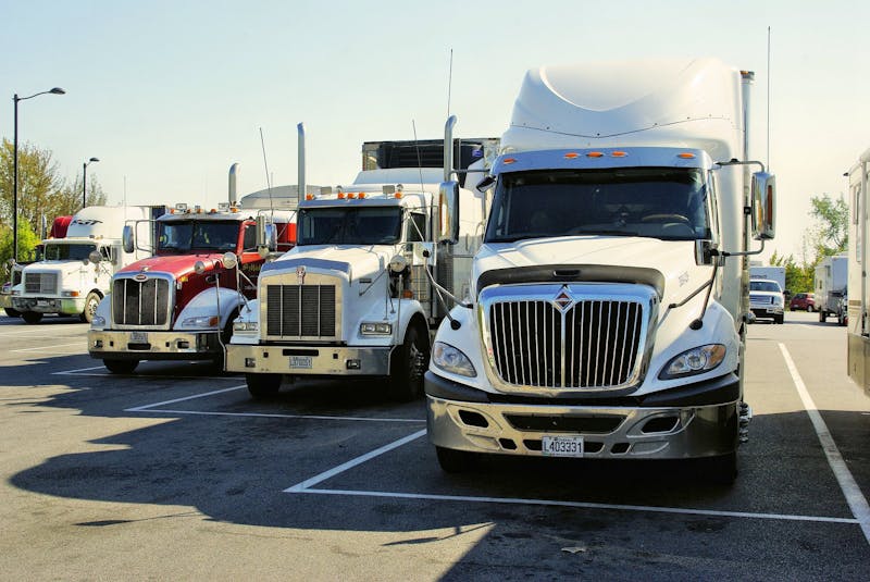 Four big 18 wheeler trucks in a parking lot.