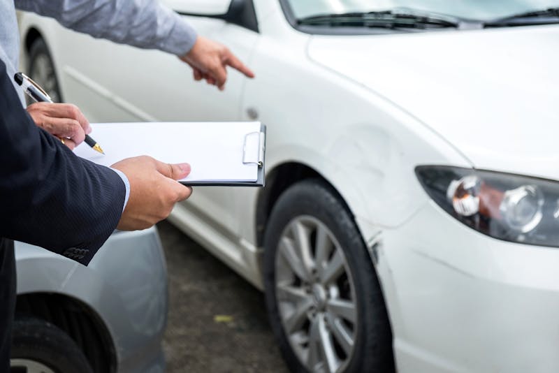 Two people assessing the damage of a car accident.