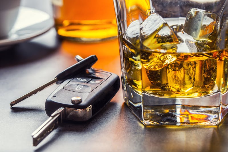 Car keys next to a cup of alcohol.