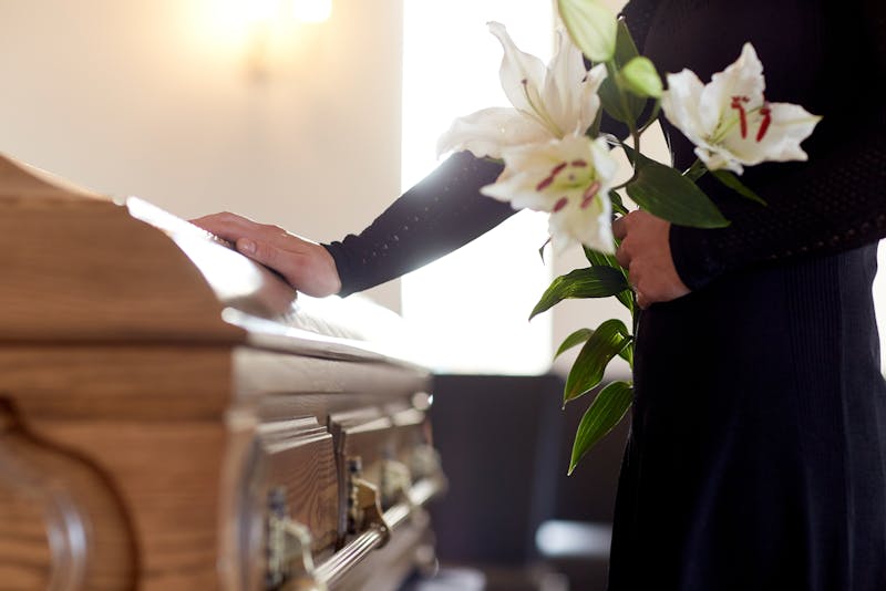 Person with a hand on a casket.