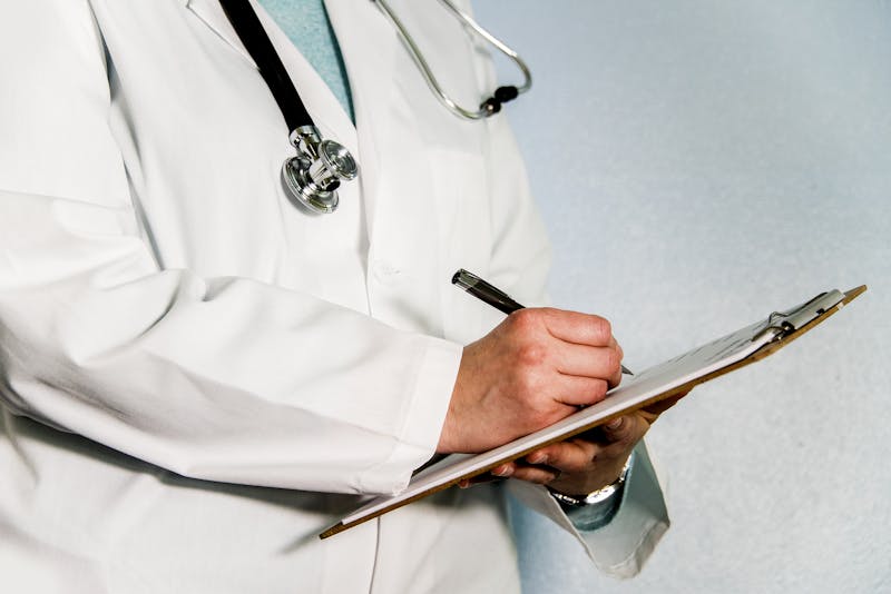 Doctor writing down info on a clipboard.