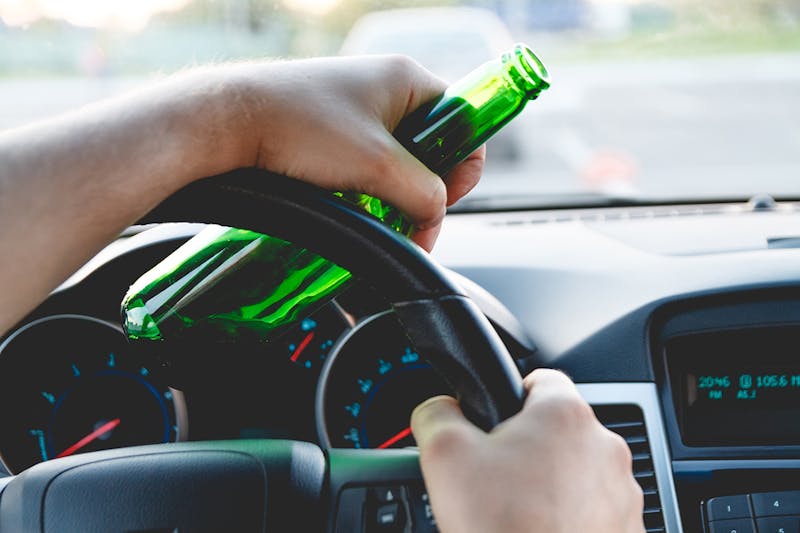 Person drinking a bottle while driving.