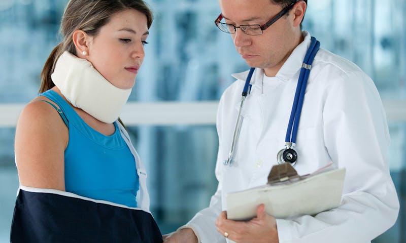 Woman in sling and neck brace talking to a doctor.