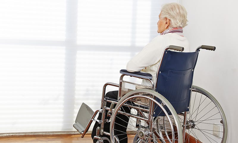 Person in a wheelchair looking out the window.