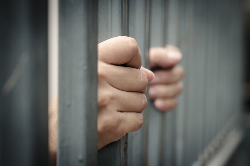 Hands on jail cell bars.