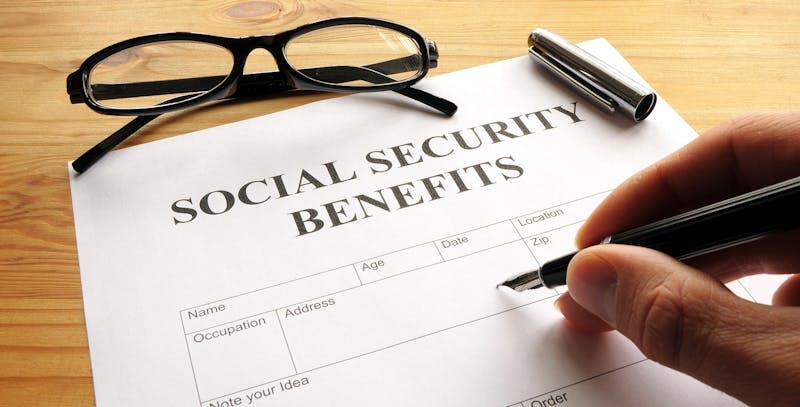 Person filling out social security benefits form.