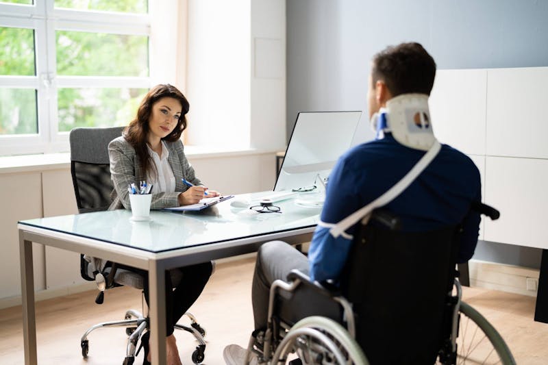 Injured person in wheelchair talking to an attorney.