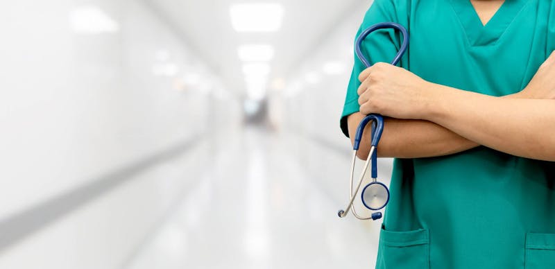 Nurse standing with crossed arms in a hospital.